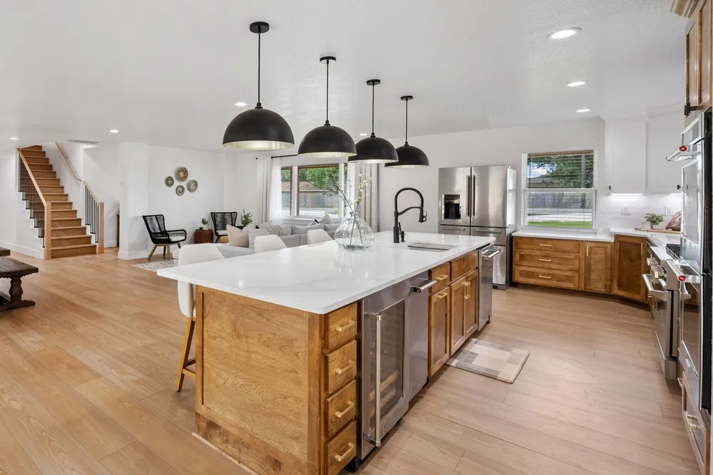 Open-plan kitchen remodel with a wood island, quartz countertop and black pendant lights