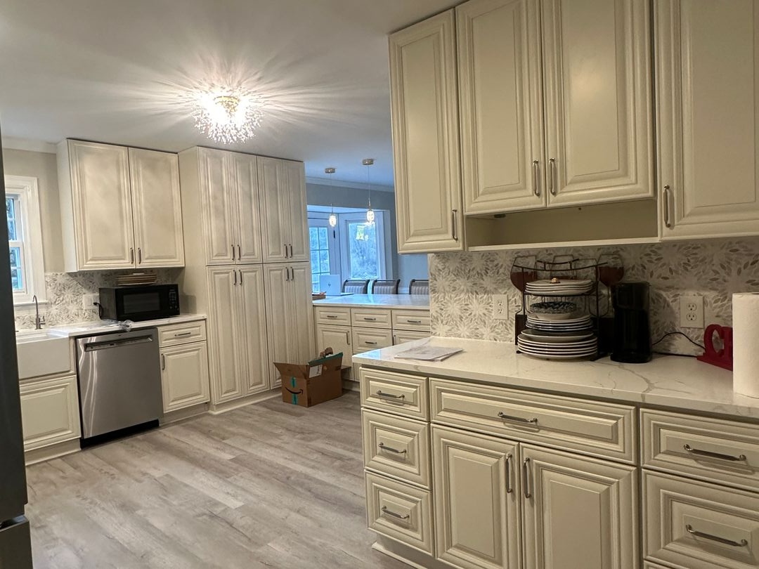 Kitchen remodel with cream raised-panel cabinetry, quartz countertops, a botanical tile backsplash and tall pantry storage